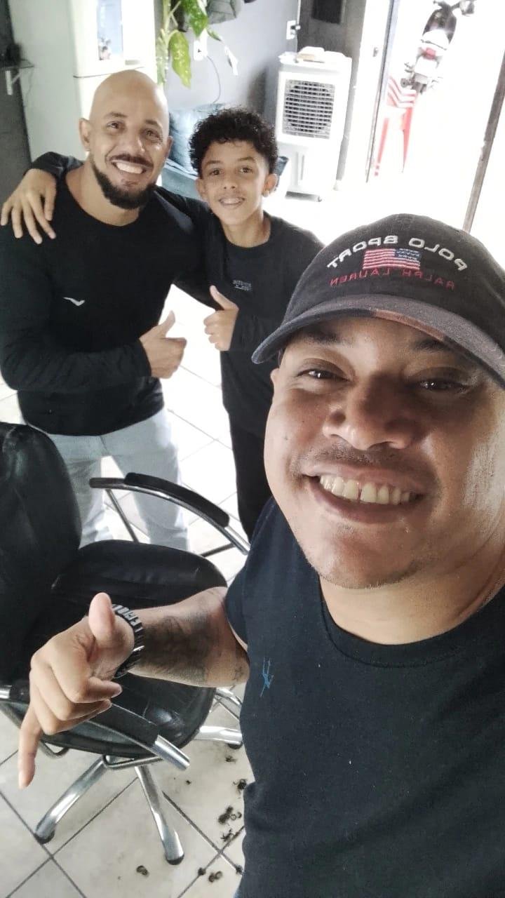 Raphael Thomas com clientes em sua barbearia